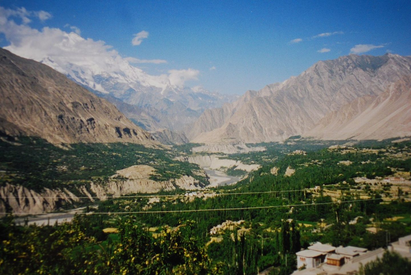 The green Hunza valley at Karimabad between bare mountains, with Rakaposhi in the distance