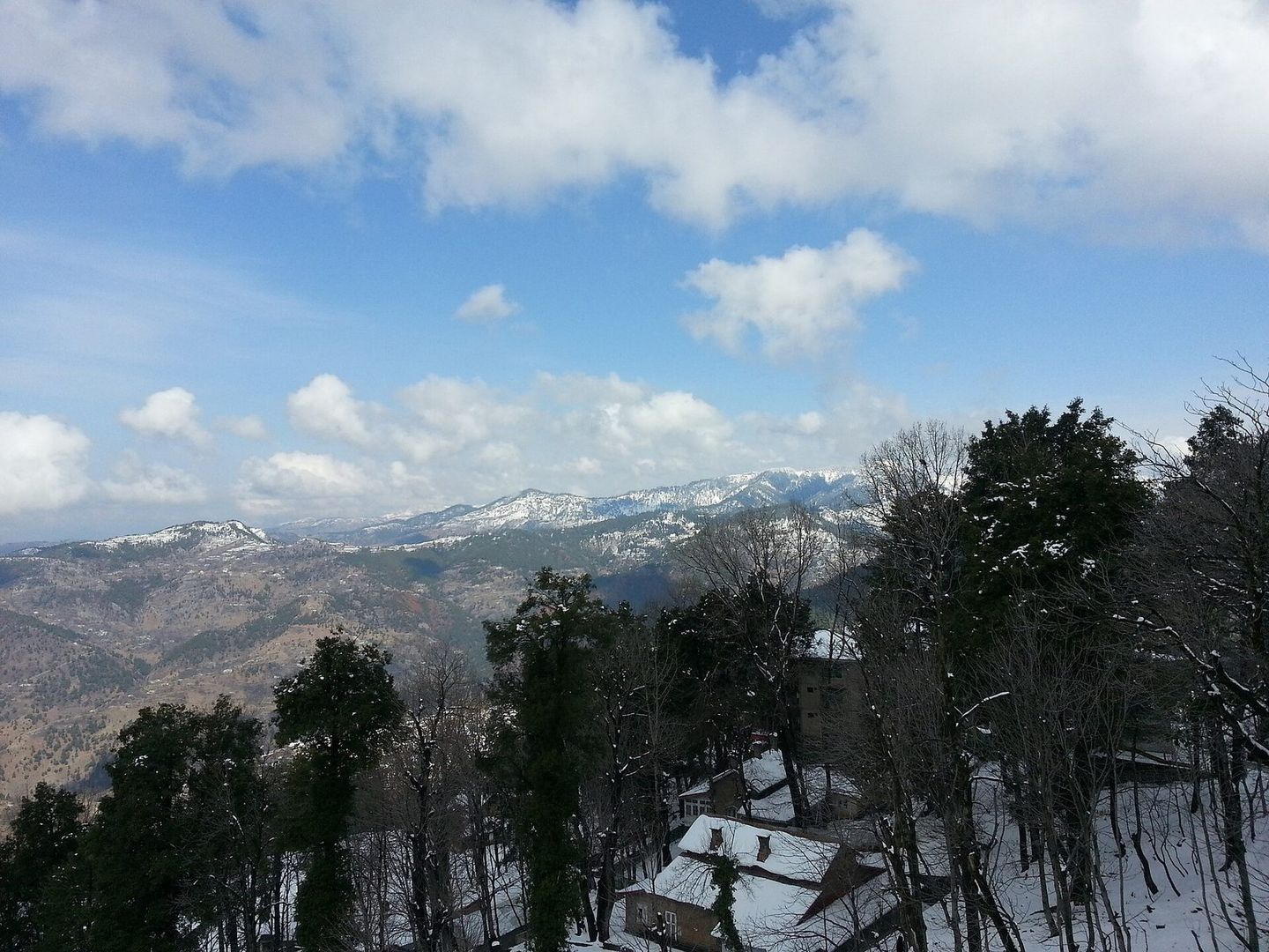 Snow among the pines at Murree, with mountains in the distance