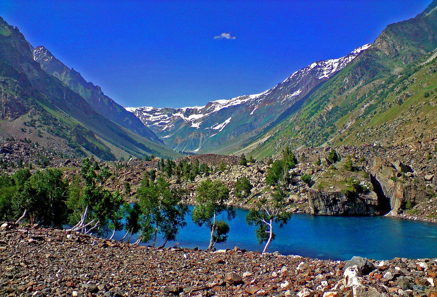 A blue lake in the Naltar Valley under snowy peaks