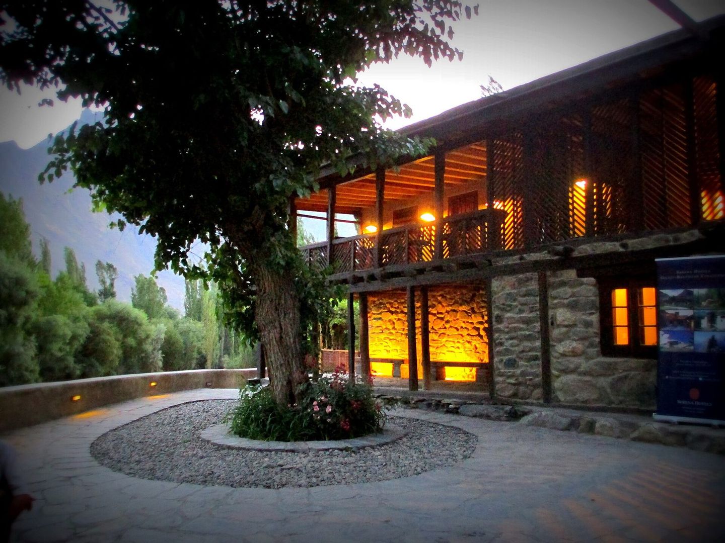 The lit courtyard and carved wooden balconies of Shigar Fort in the evening