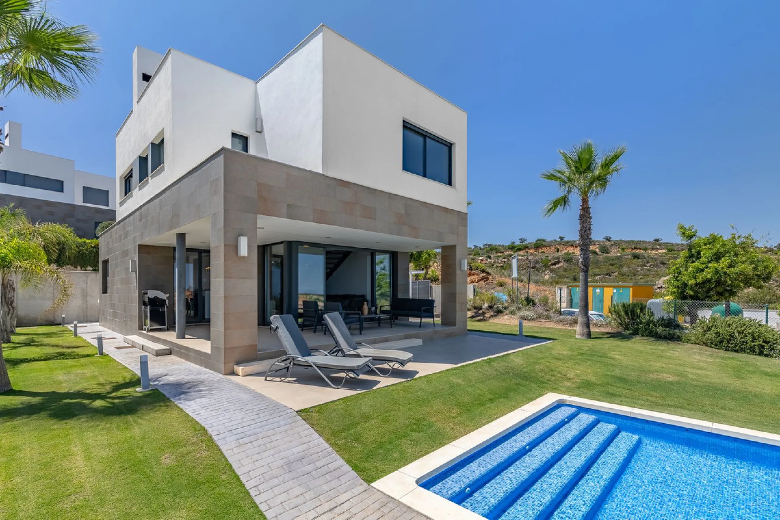 This stunning two-story villa boasts four spacious bedrooms, each with fitted wardrobes, electric blinds, and individual air conditioning control. The three elegant bathrooms feature the comfort of underfloor heating.