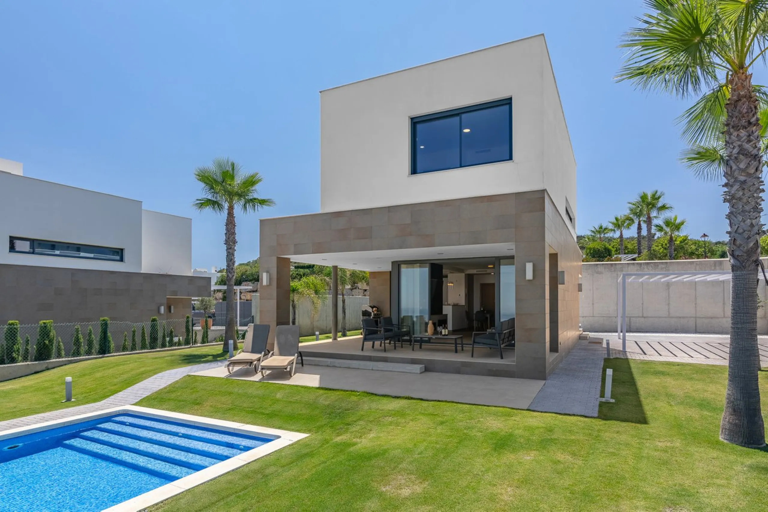 This stunning two-story villa boasts four spacious bedrooms, each with fitted wardrobes, electric blinds, and individual air conditioning control. The three elegant bathrooms feature the comfort of underfloor heating.