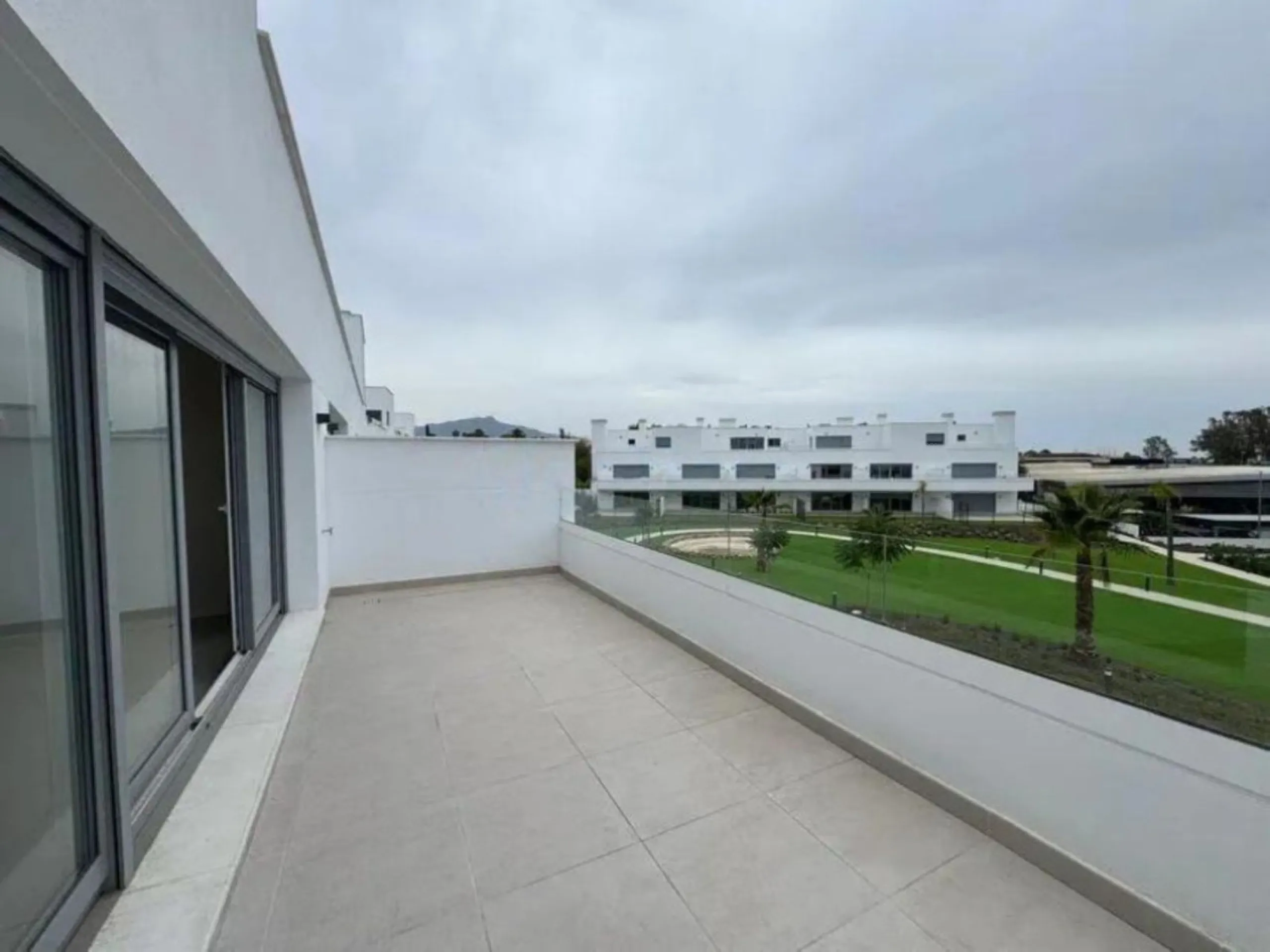 This bright, unfurnished 2-bedroom apartment pairs a practical layout with a calm outlook over the green communal landscape and a distant sea view from the terrace.