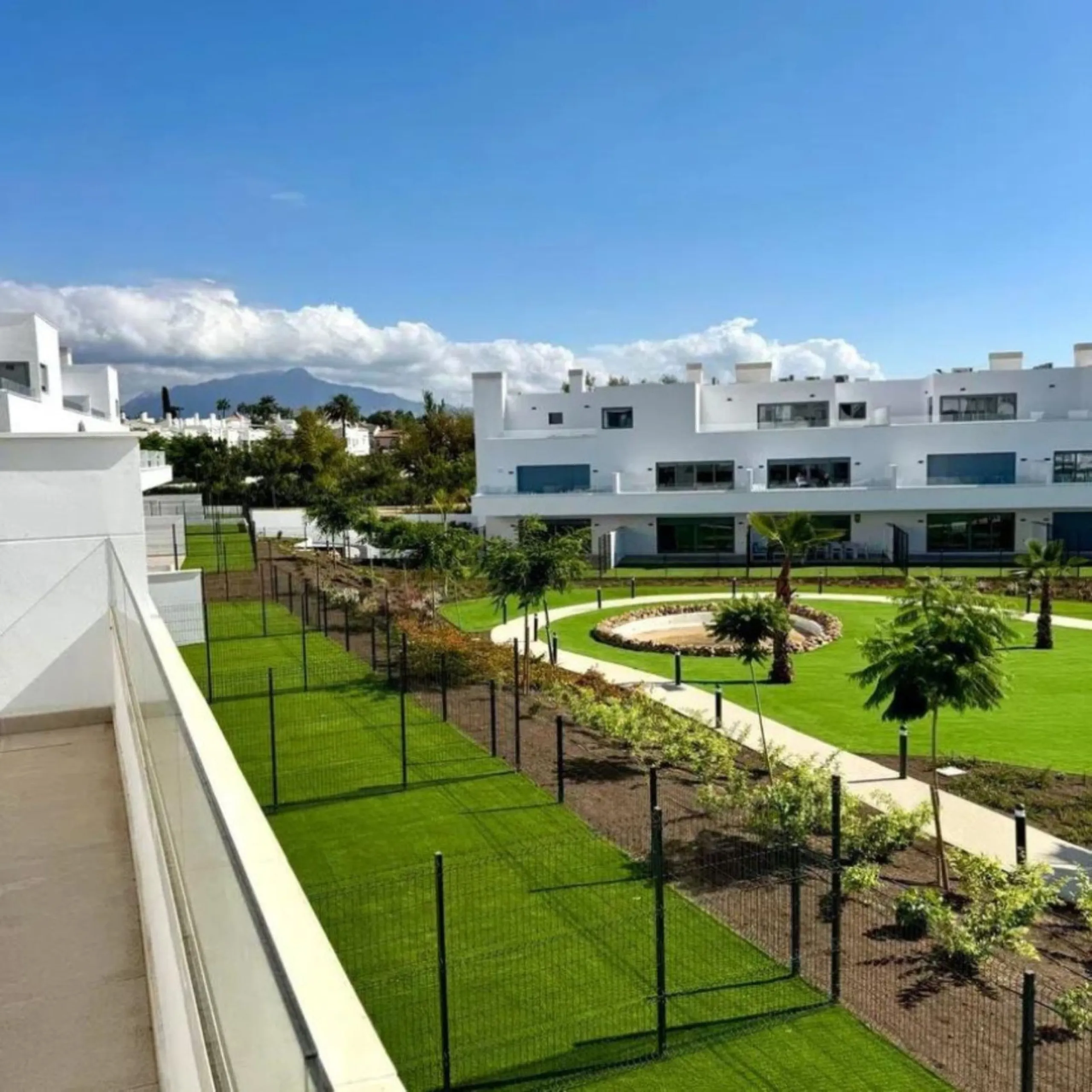 This bright, unfurnished 2-bedroom apartment pairs a practical layout with a calm outlook over the green communal landscape and a distant sea view from the terrace.