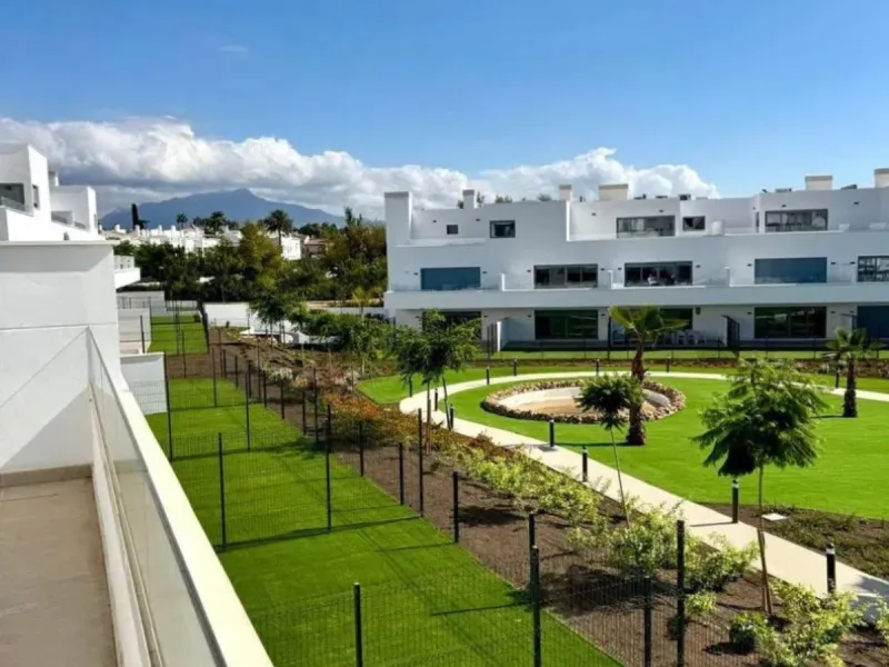 This bright, unfurnished 2-bedroom apartment pairs a practical layout with a calm outlook over the green communal landscape and a distant sea view from the terrace.
