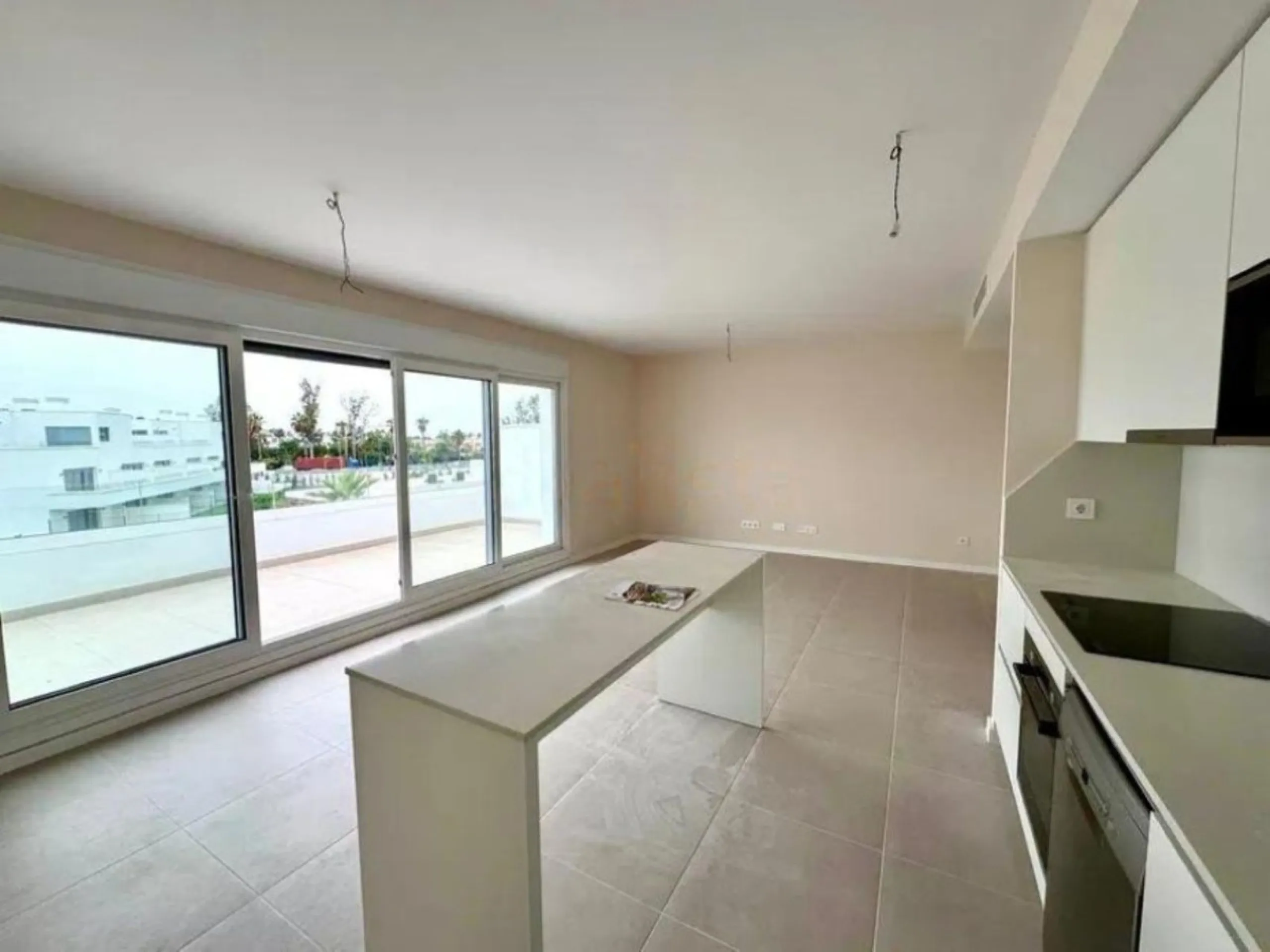 This bright, unfurnished 2-bedroom apartment pairs a practical layout with a calm outlook over the green communal landscape and a distant sea view from the terrace.