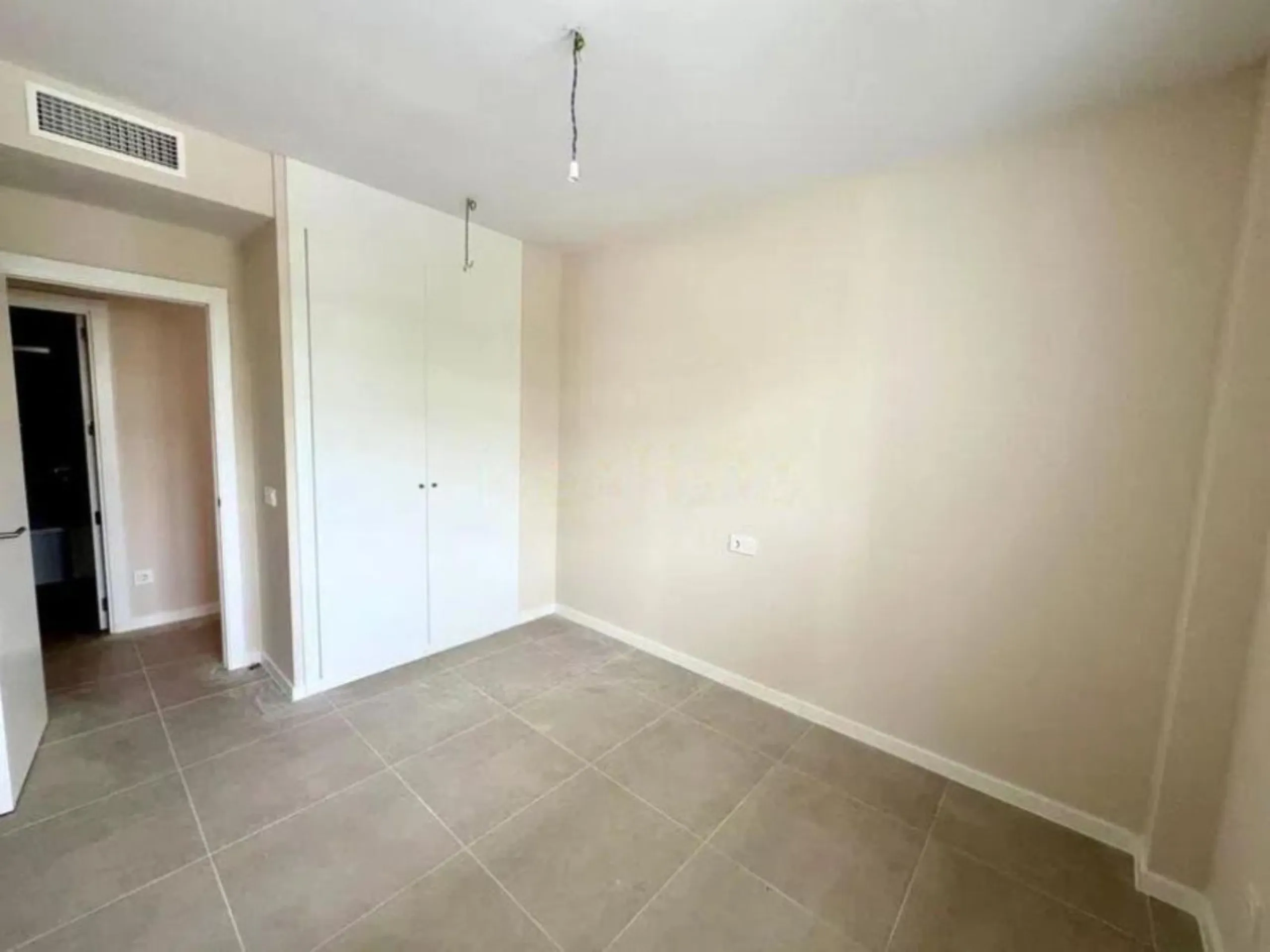 This bright, unfurnished 2-bedroom apartment pairs a practical layout with a calm outlook over the green communal landscape and a distant sea view from the terrace.