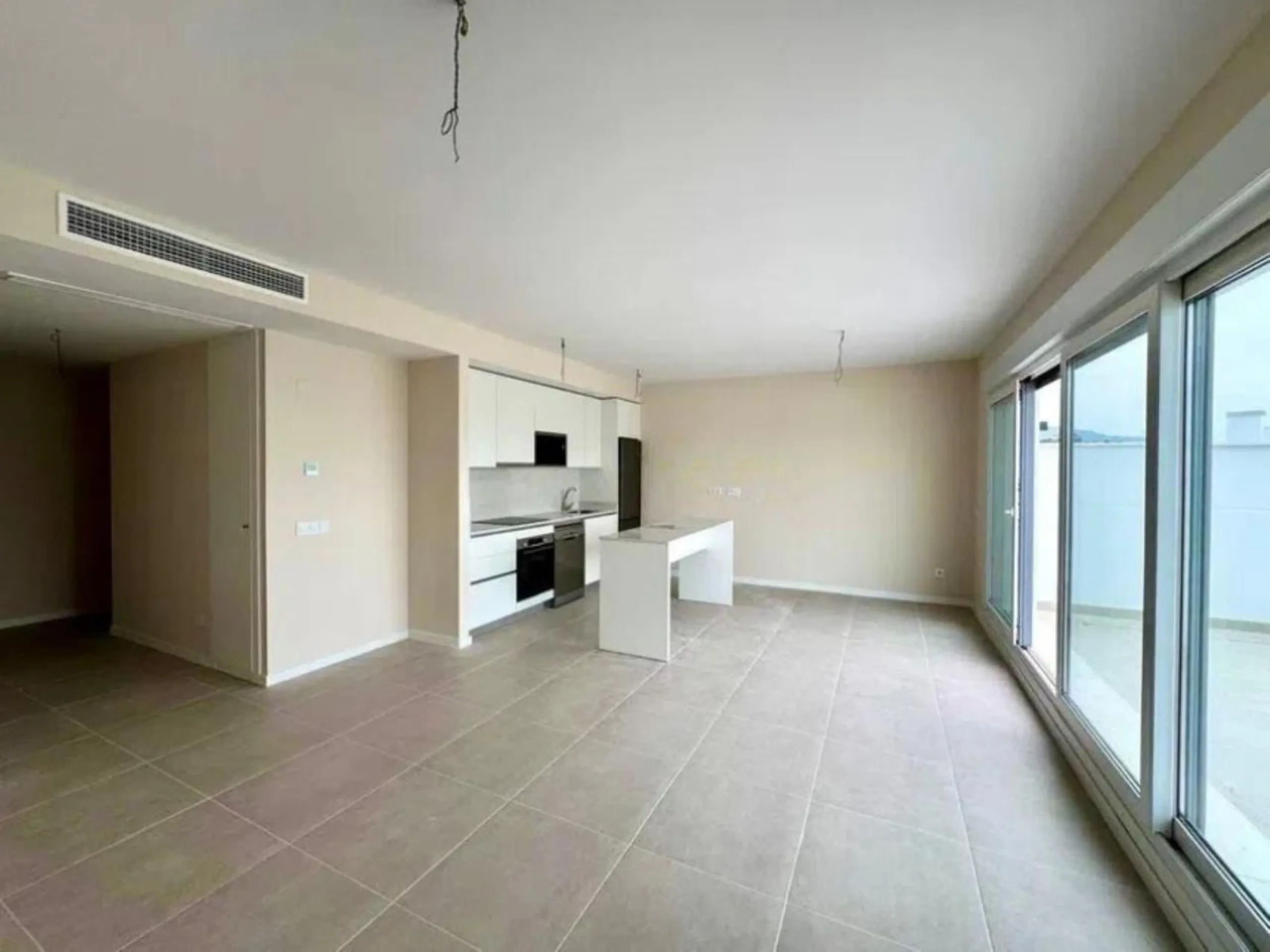 This bright, unfurnished 2-bedroom apartment pairs a practical layout with a calm outlook over the green communal landscape and a distant sea view from the terrace.