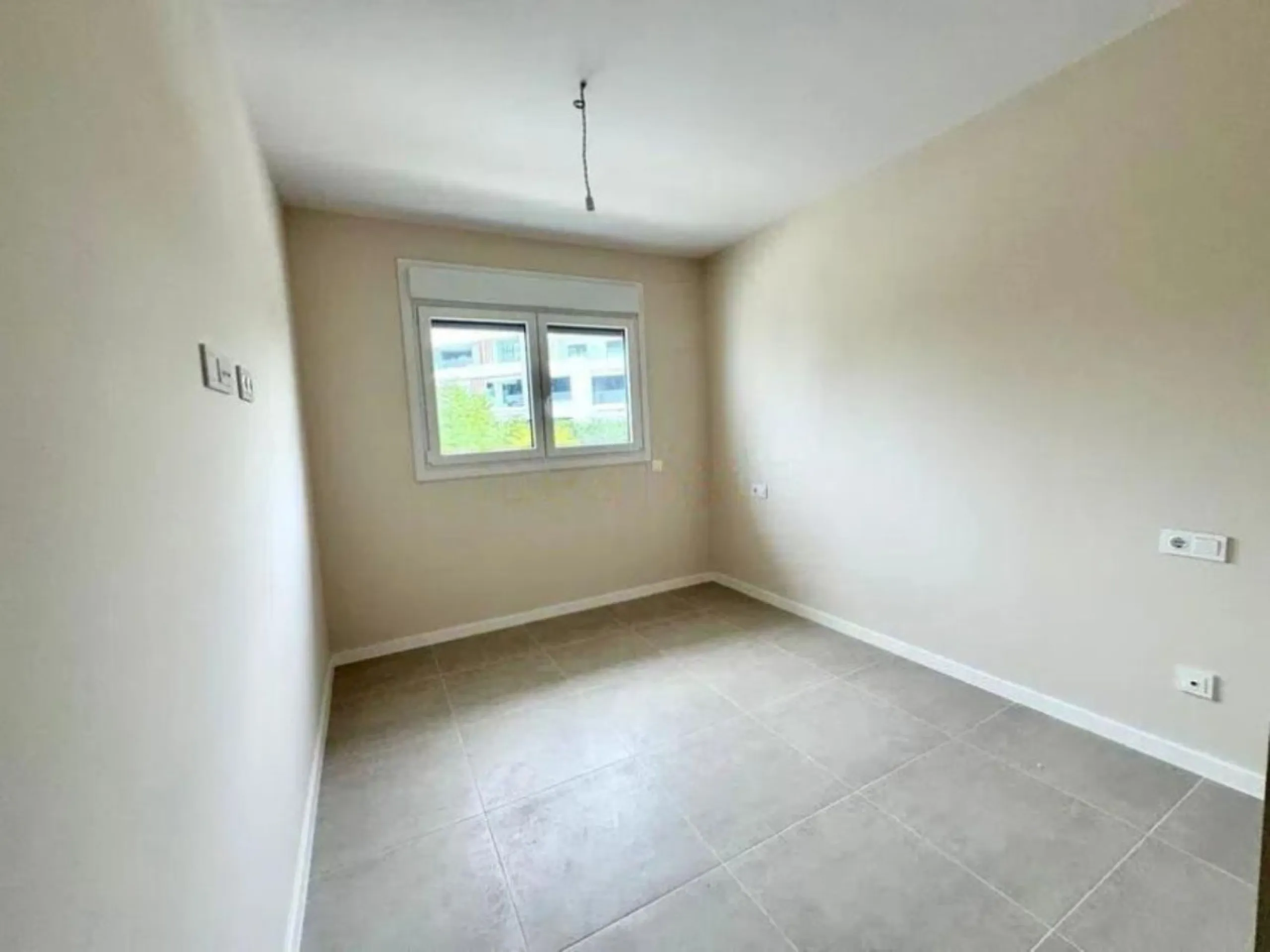 This bright, unfurnished 2-bedroom apartment pairs a practical layout with a calm outlook over the green communal landscape and a distant sea view from the terrace.