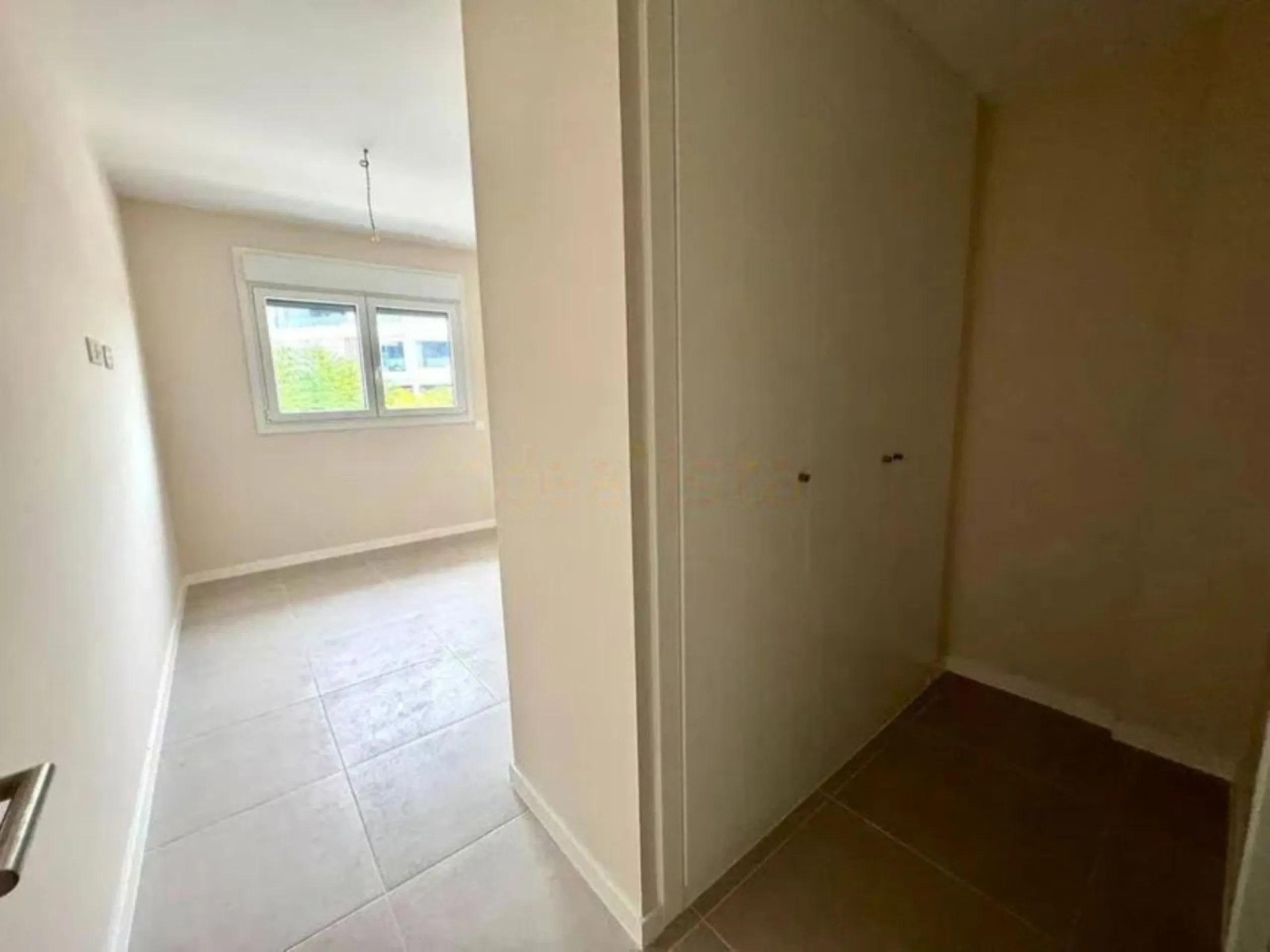 This bright, unfurnished 2-bedroom apartment pairs a practical layout with a calm outlook over the green communal landscape and a distant sea view from the terrace.