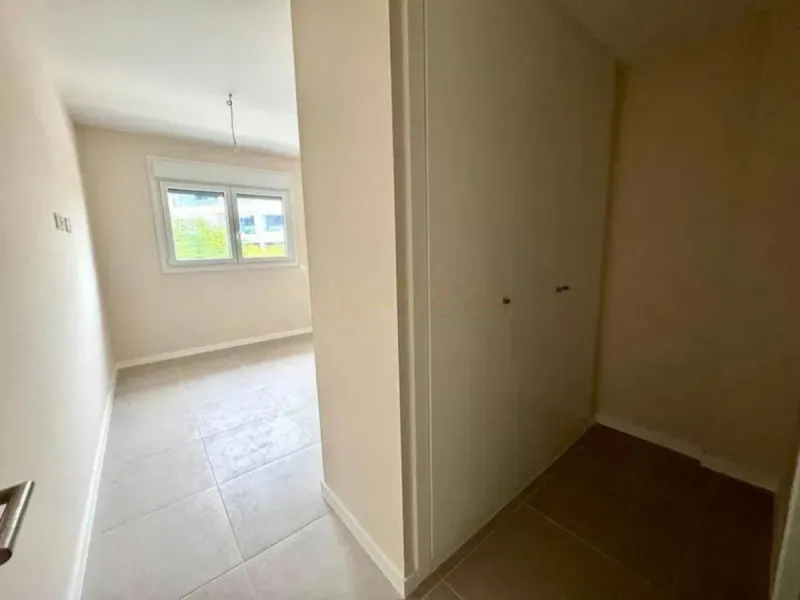 This bright, unfurnished 2-bedroom apartment pairs a practical layout with a calm outlook over the green communal landscape and a distant sea view from the terrace.