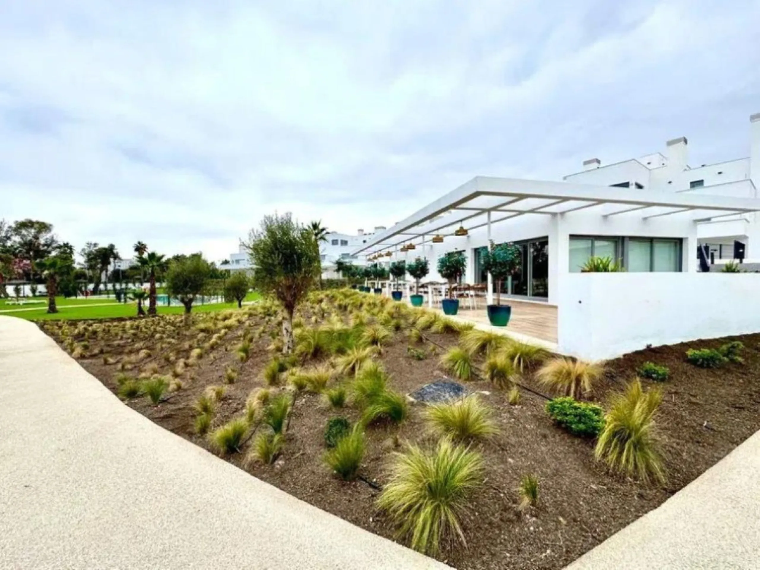 This bright, unfurnished 2-bedroom apartment pairs a practical layout with a calm outlook over the green communal landscape and a distant sea view from the terrace.