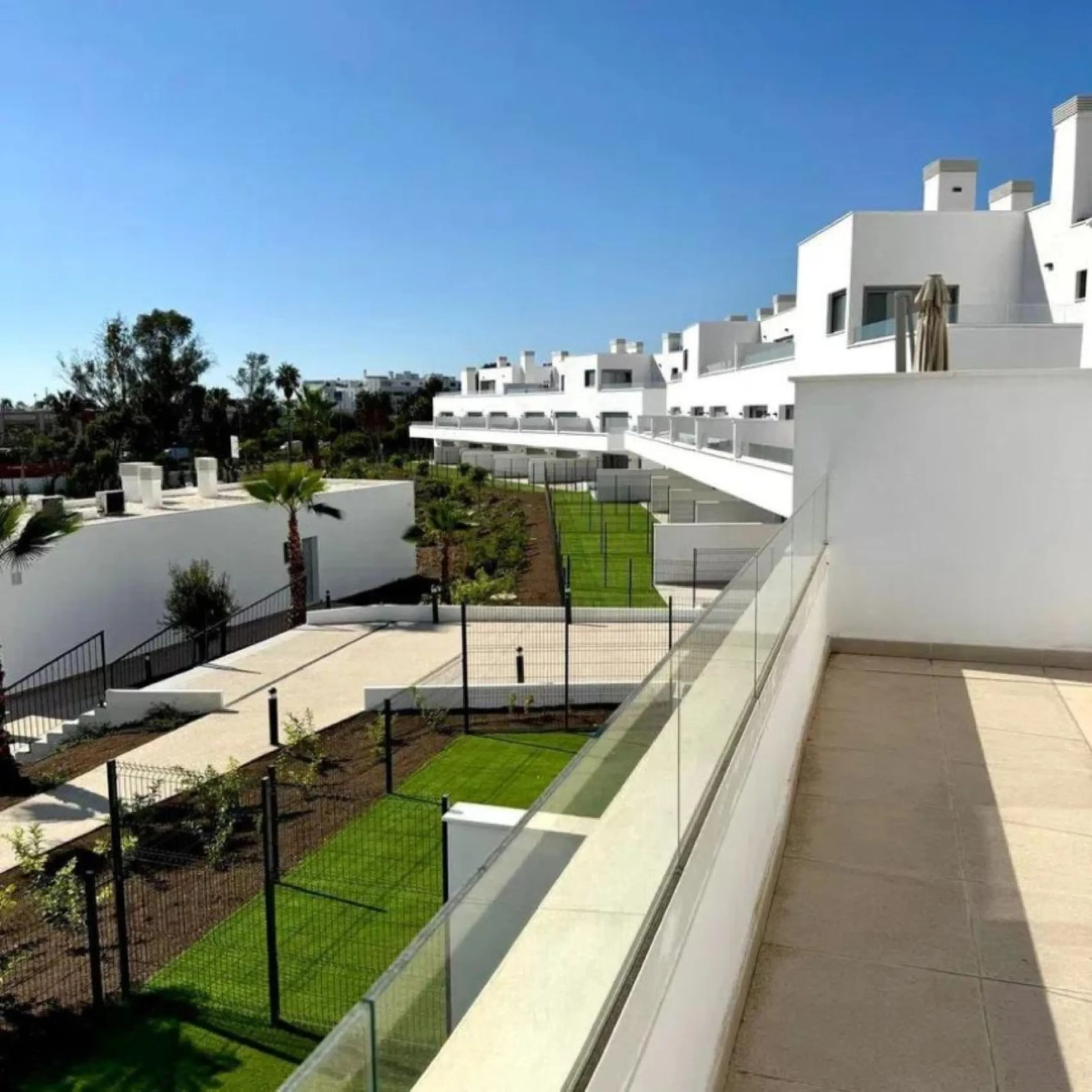 This bright, unfurnished 2-bedroom apartment pairs a practical layout with a calm outlook over the green communal landscape and a distant sea view from the terrace.