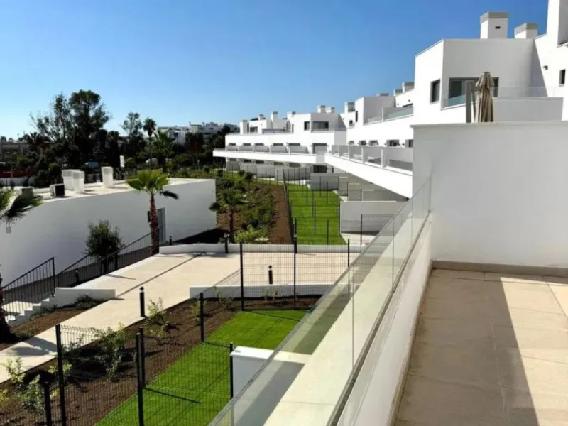 This bright, unfurnished 2-bedroom apartment pairs a practical layout with a calm outlook over the green communal landscape and a distant sea view from the terrace.