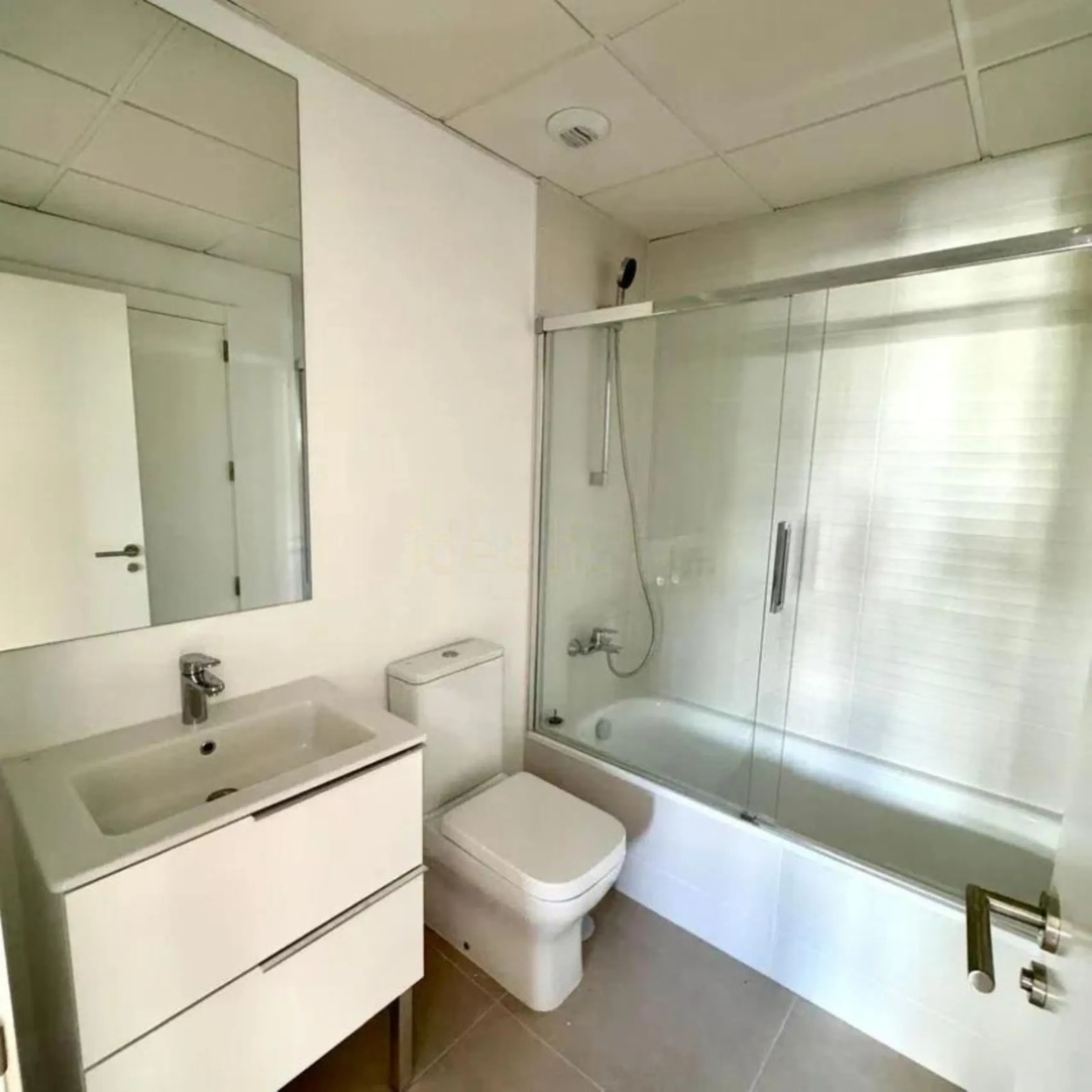 This bright, unfurnished 2-bedroom apartment pairs a practical layout with a calm outlook over the green communal landscape and a distant sea view from the terrace.