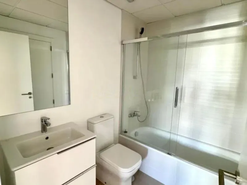 This bright, unfurnished 2-bedroom apartment pairs a practical layout with a calm outlook over the green communal landscape and a distant sea view from the terrace.
