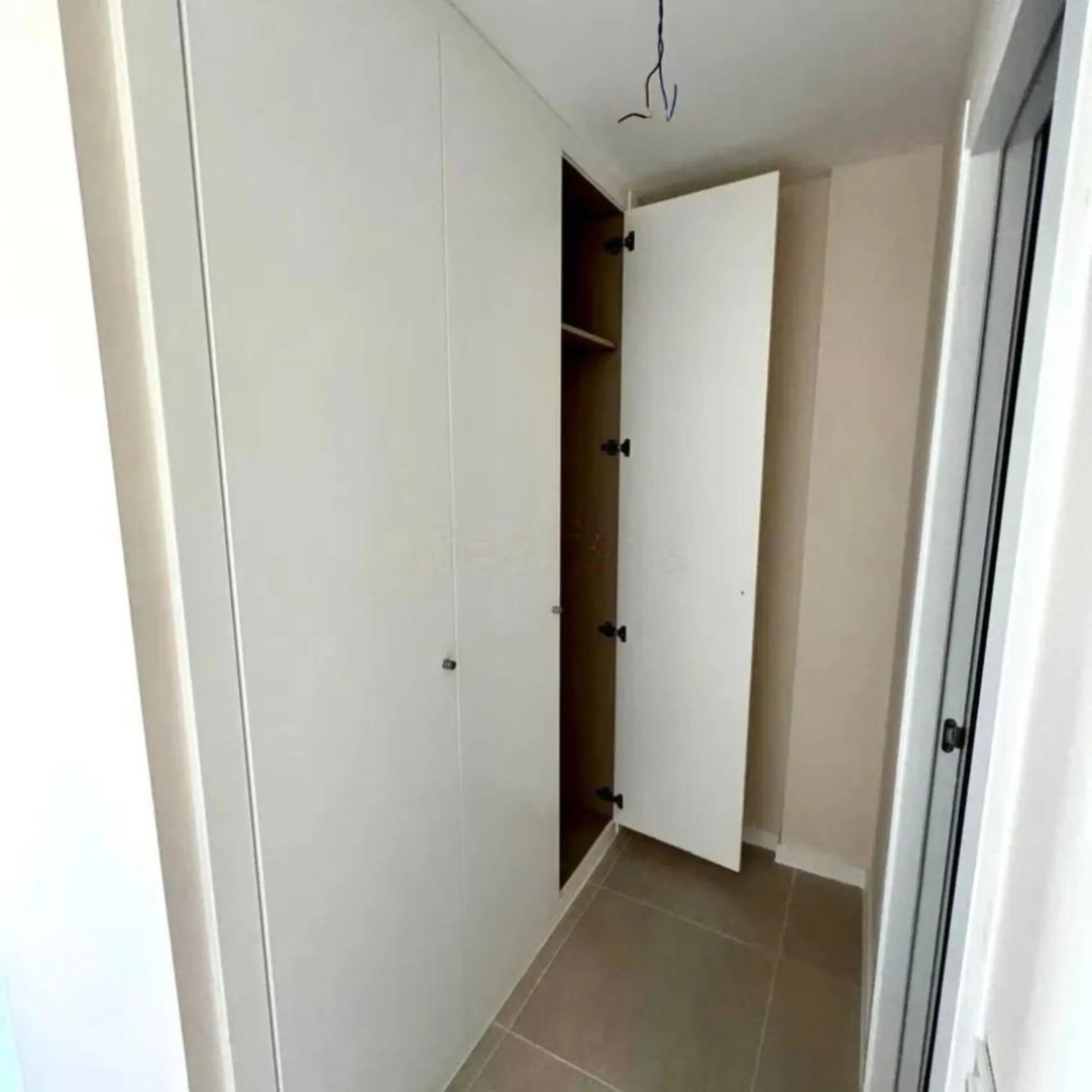 This bright, unfurnished 2-bedroom apartment pairs a practical layout with a calm outlook over the green communal landscape and a distant sea view from the terrace.