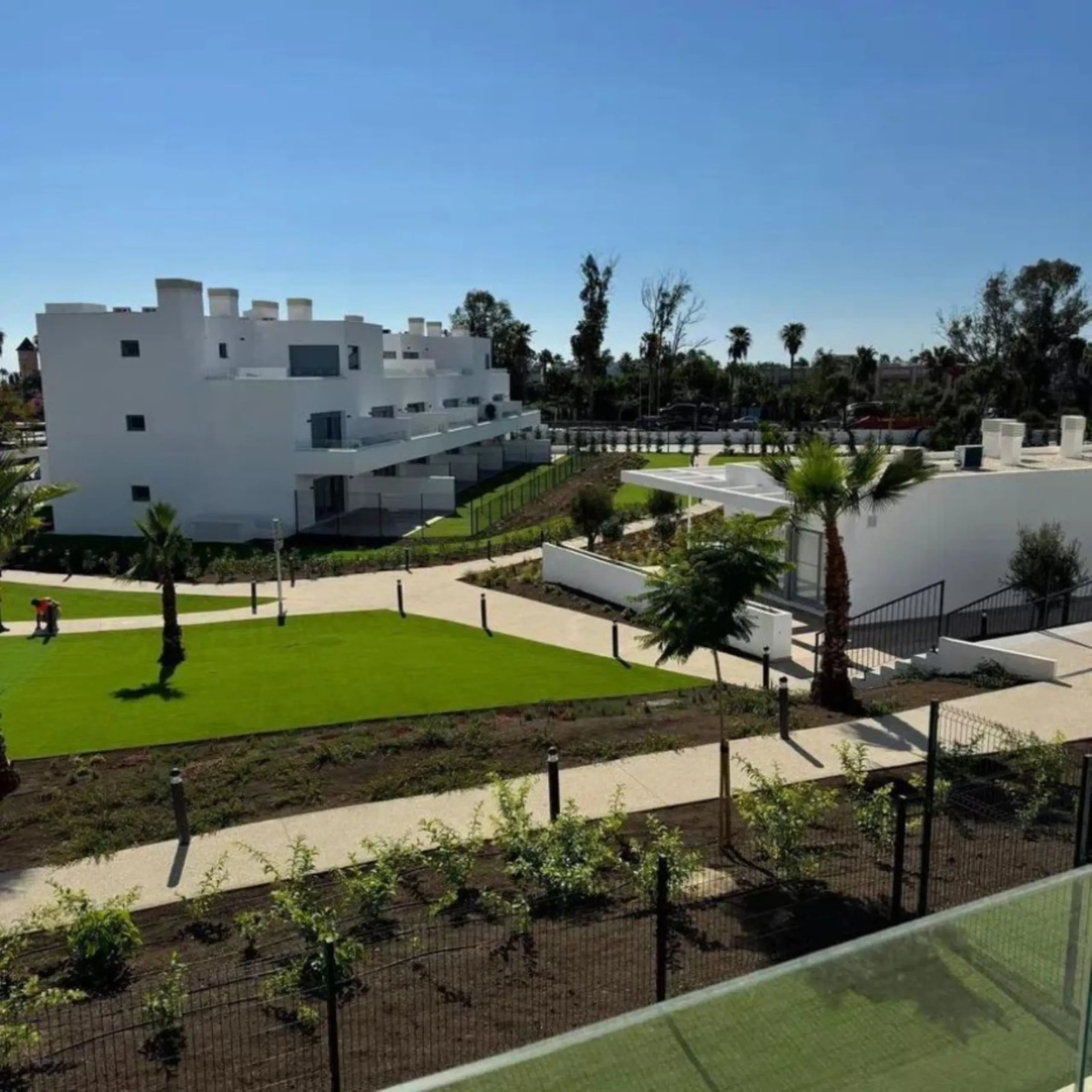 This bright, unfurnished 2-bedroom apartment pairs a practical layout with a calm outlook over the green communal landscape and a distant sea view from the terrace.