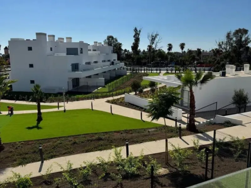 This bright, unfurnished 2-bedroom apartment pairs a practical layout with a calm outlook over the green communal landscape and a distant sea view from the terrace.