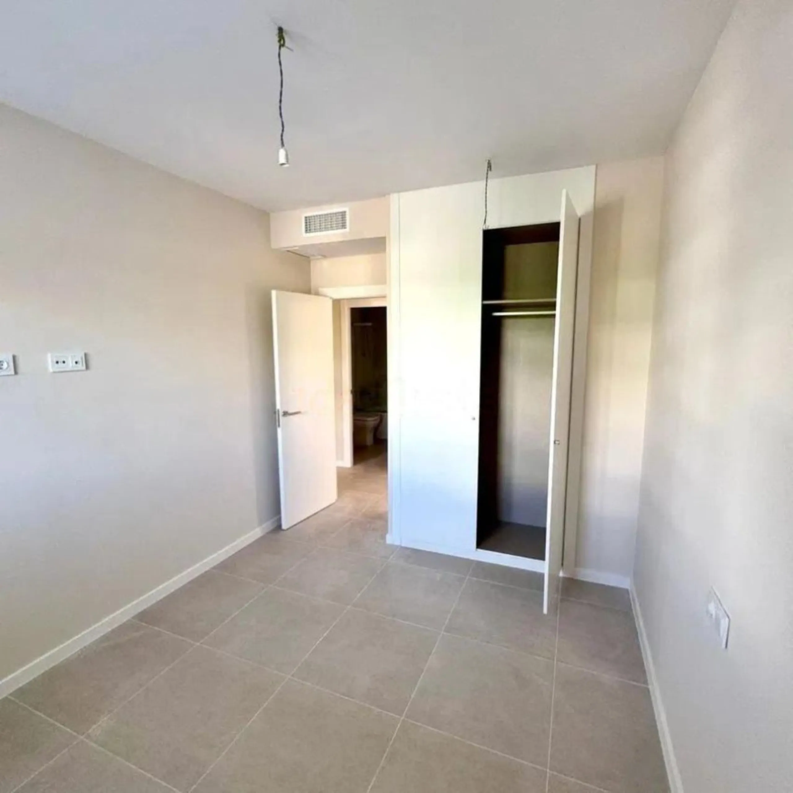 This bright, unfurnished 2-bedroom apartment pairs a practical layout with a calm outlook over the green communal landscape and a distant sea view from the terrace.