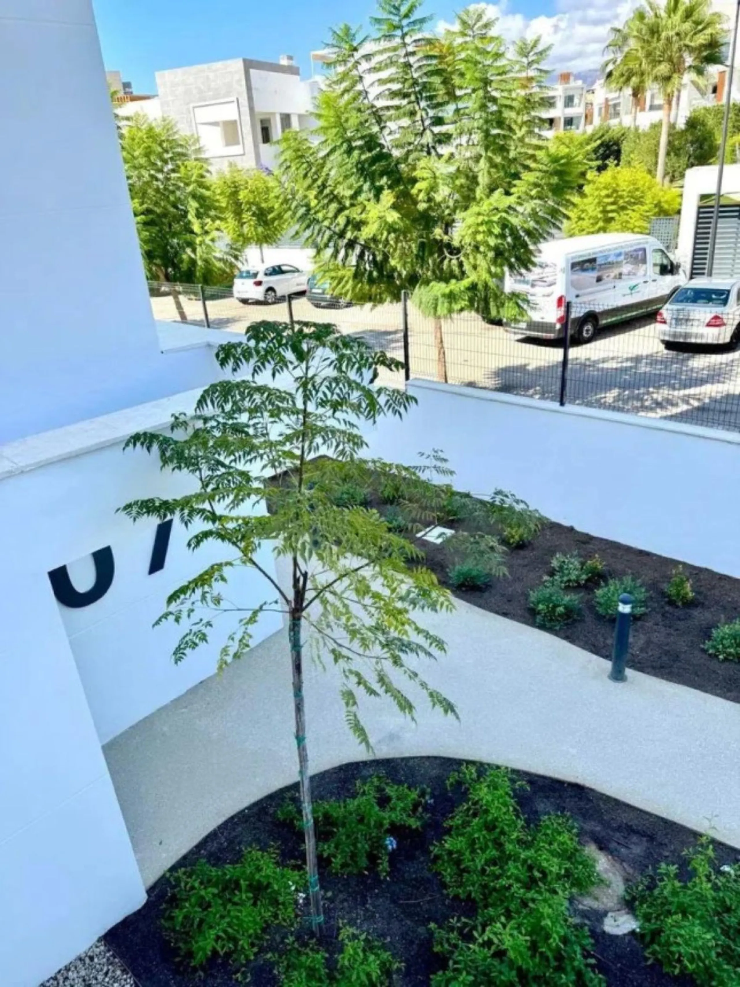This bright, unfurnished 2-bedroom apartment pairs a practical layout with a calm outlook over the green communal landscape and a distant sea view from the terrace.