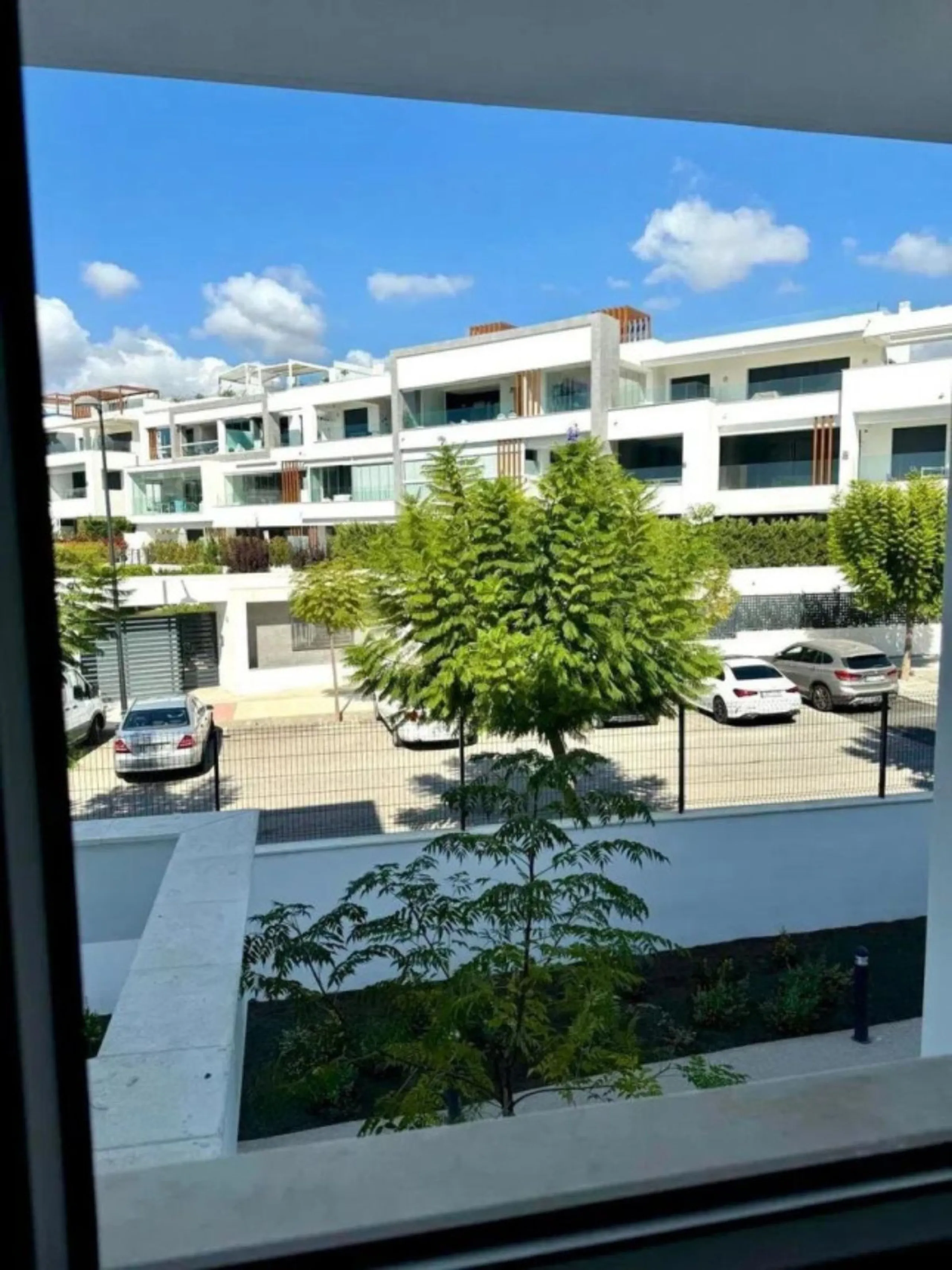 This bright, unfurnished 2-bedroom apartment pairs a practical layout with a calm outlook over the green communal landscape and a distant sea view from the terrace.