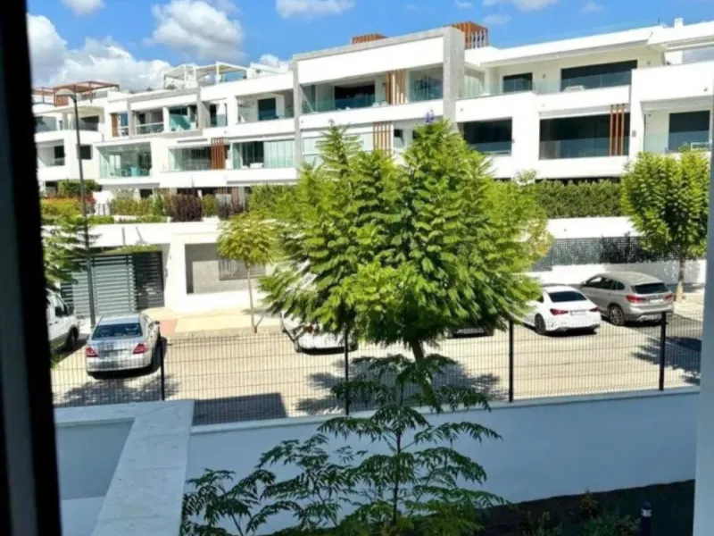 This bright, unfurnished 2-bedroom apartment pairs a practical layout with a calm outlook over the green communal landscape and a distant sea view from the terrace.
