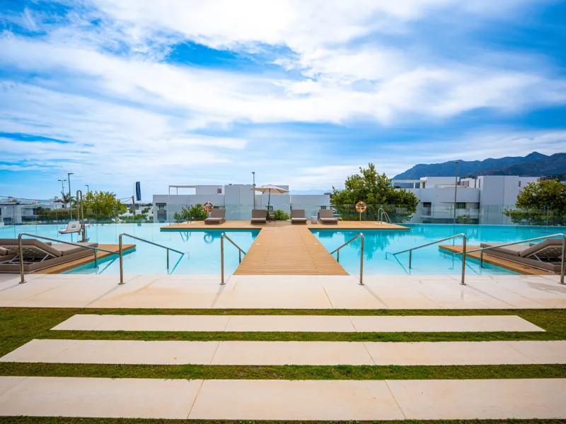 Penthouse Alma is a brand-new duplex home in a secure gated community in Marbella East. It has two ensuite bedrooms, a guest bathroom, and an open-plan living space that connects the kitchen, dining, and lounge areas. Floor-to-ceiling windows fill the hom