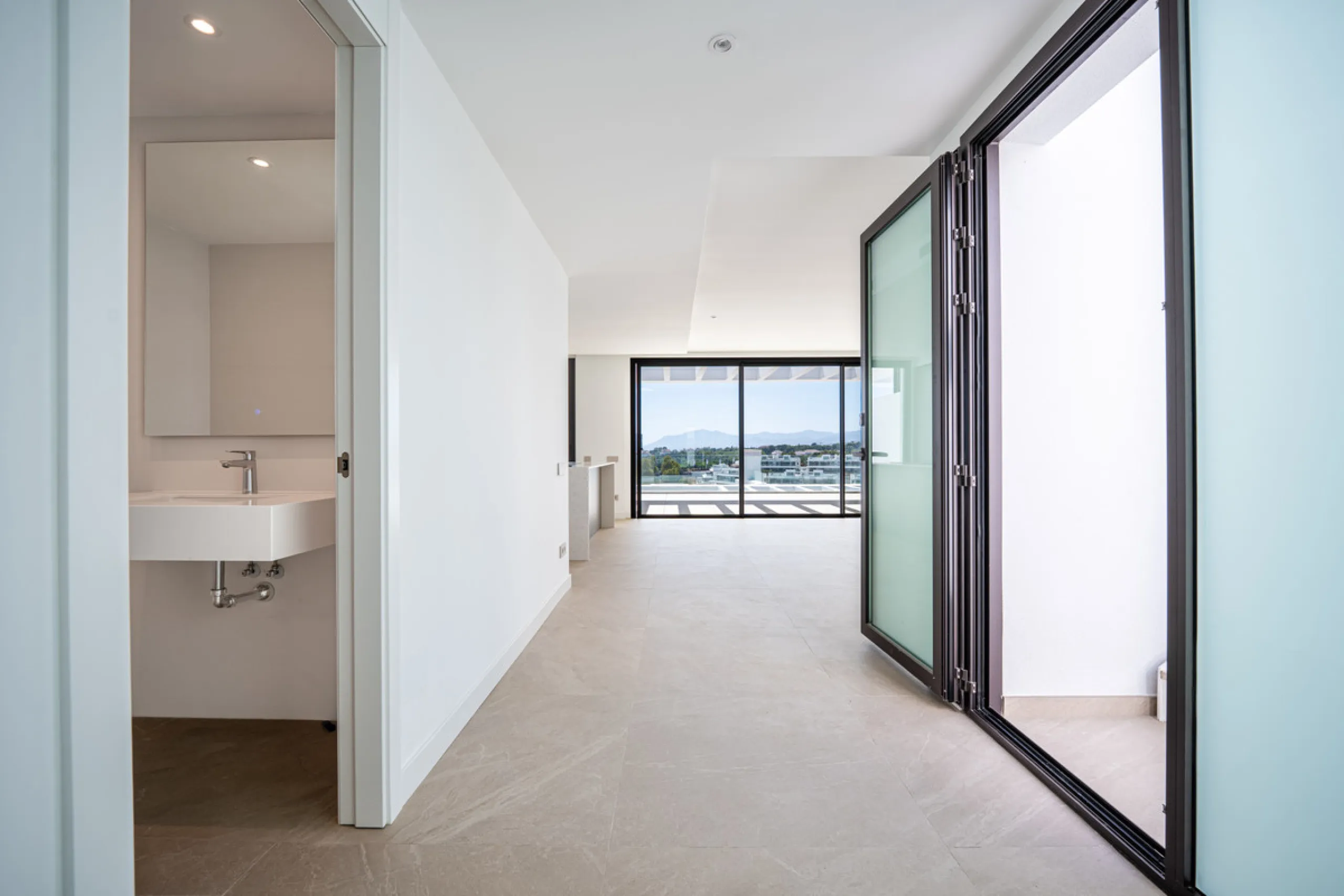 Penthouse Alma is a brand-new duplex home in a secure gated community in Marbella East. It has two ensuite bedrooms, a guest bathroom, and an open-plan living space that connects the kitchen, dining, and lounge areas. Floor-to-ceiling windows fill the hom