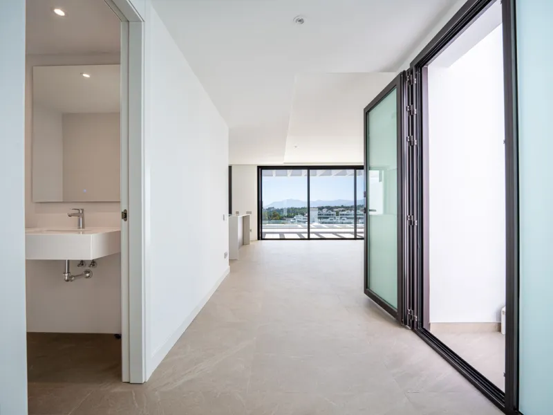 Penthouse Alma is a brand-new duplex home in a secure gated community in Marbella East. It has two ensuite bedrooms, a guest bathroom, and an open-plan living space that connects the kitchen, dining, and lounge areas. Floor-to-ceiling windows fill the hom