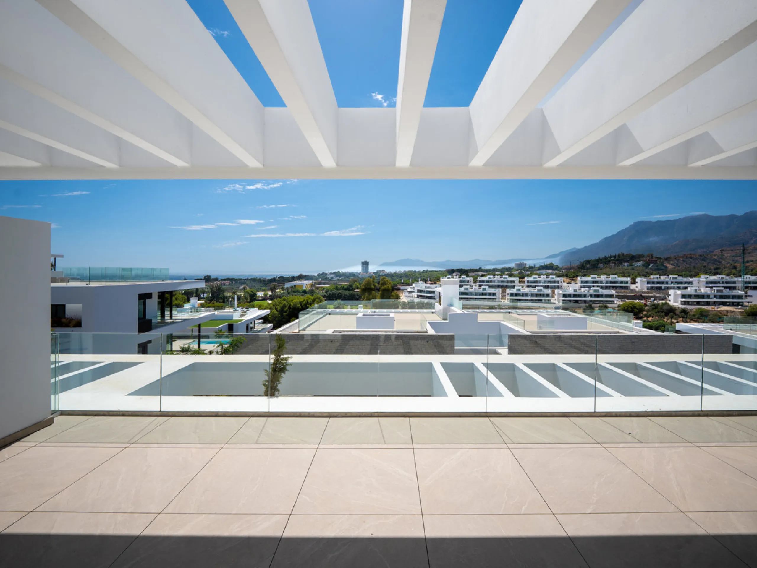 Penthouse Alma is a brand-new duplex home in a secure gated community in Marbella East. It has two ensuite bedrooms, a guest bathroom, and an open-plan living space that connects the kitchen, dining, and lounge areas. Floor-to-ceiling windows fill the hom