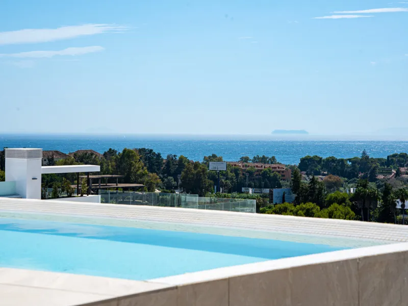 Penthouse Alma is a brand-new duplex home in a secure gated community in Marbella East. It has two ensuite bedrooms, a guest bathroom, and an open-plan living space that connects the kitchen, dining, and lounge areas. Floor-to-ceiling windows fill the hom