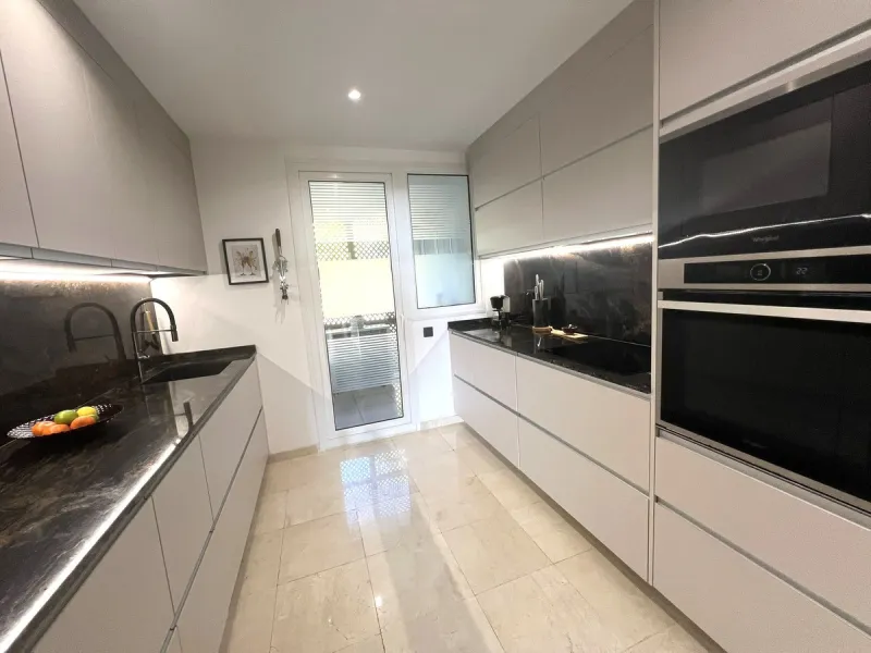 Discover this exceptional first-floor corner apartment, where modern comfort meets breathtaking scenery. Boasting two expansive, glassed in terraces, the residence offers panoramic views that stretch from the sparkling Mediterranean Sea to the majestic su