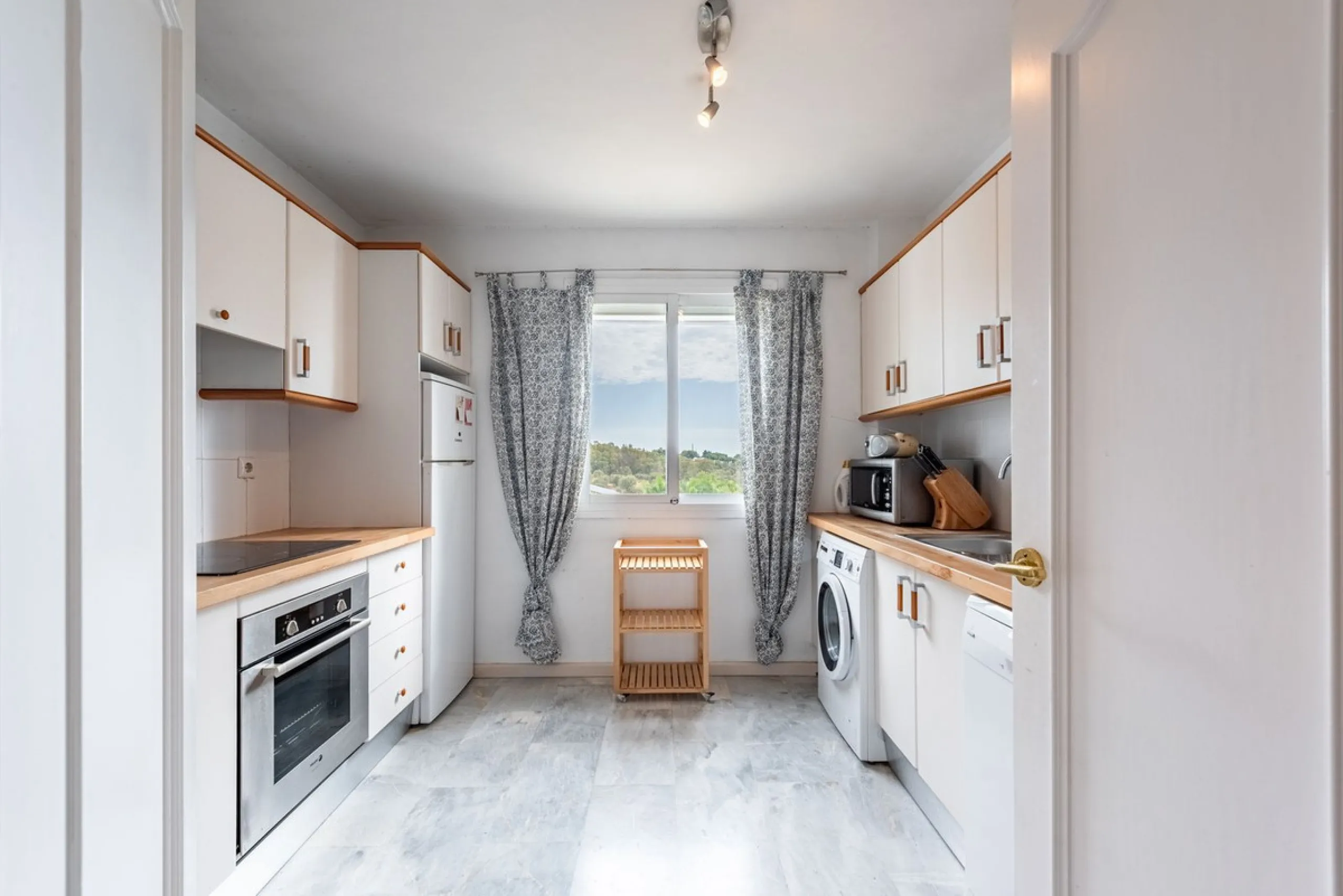 Bright and spacious apartment located in the sought-after Las Jacarandas complex in Bel Air, Estepona. Situated on the first floor, this corner unit enjoys an abundance of natural light and offers tranquil green views with glimpses of the mountains and di