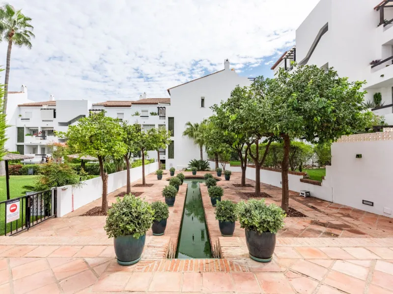 Bright and spacious apartment located in the sought-after Las Jacarandas complex in Bel Air, Estepona. Situated on the first floor, this corner unit enjoys an abundance of natural light and offers tranquil green views with glimpses of the mountains and di