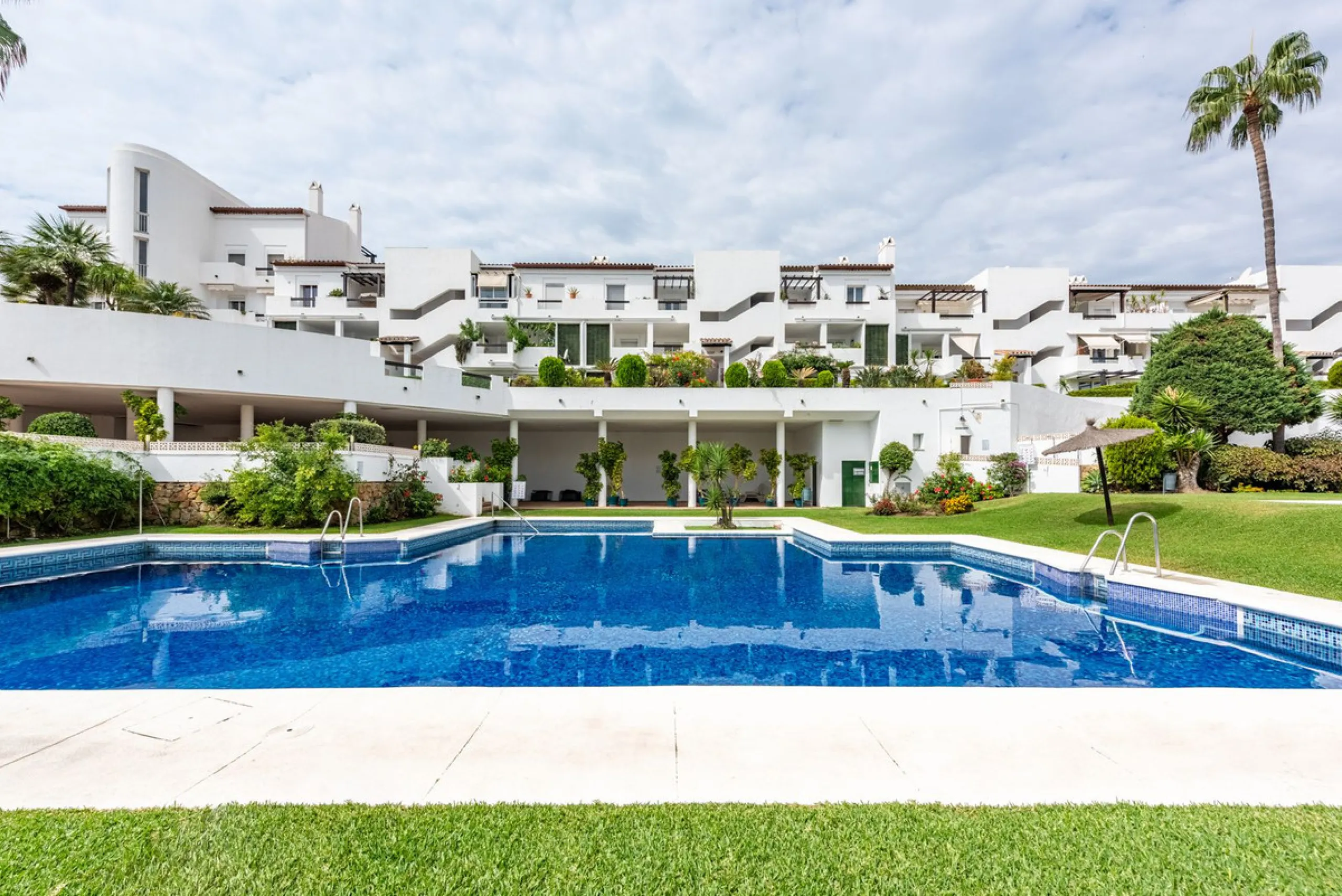 Bright and spacious apartment located in the sought-after Las Jacarandas complex in Bel Air, Estepona. Situated on the first floor, this corner unit enjoys an abundance of natural light and offers tranquil green views with glimpses of the mountains and di