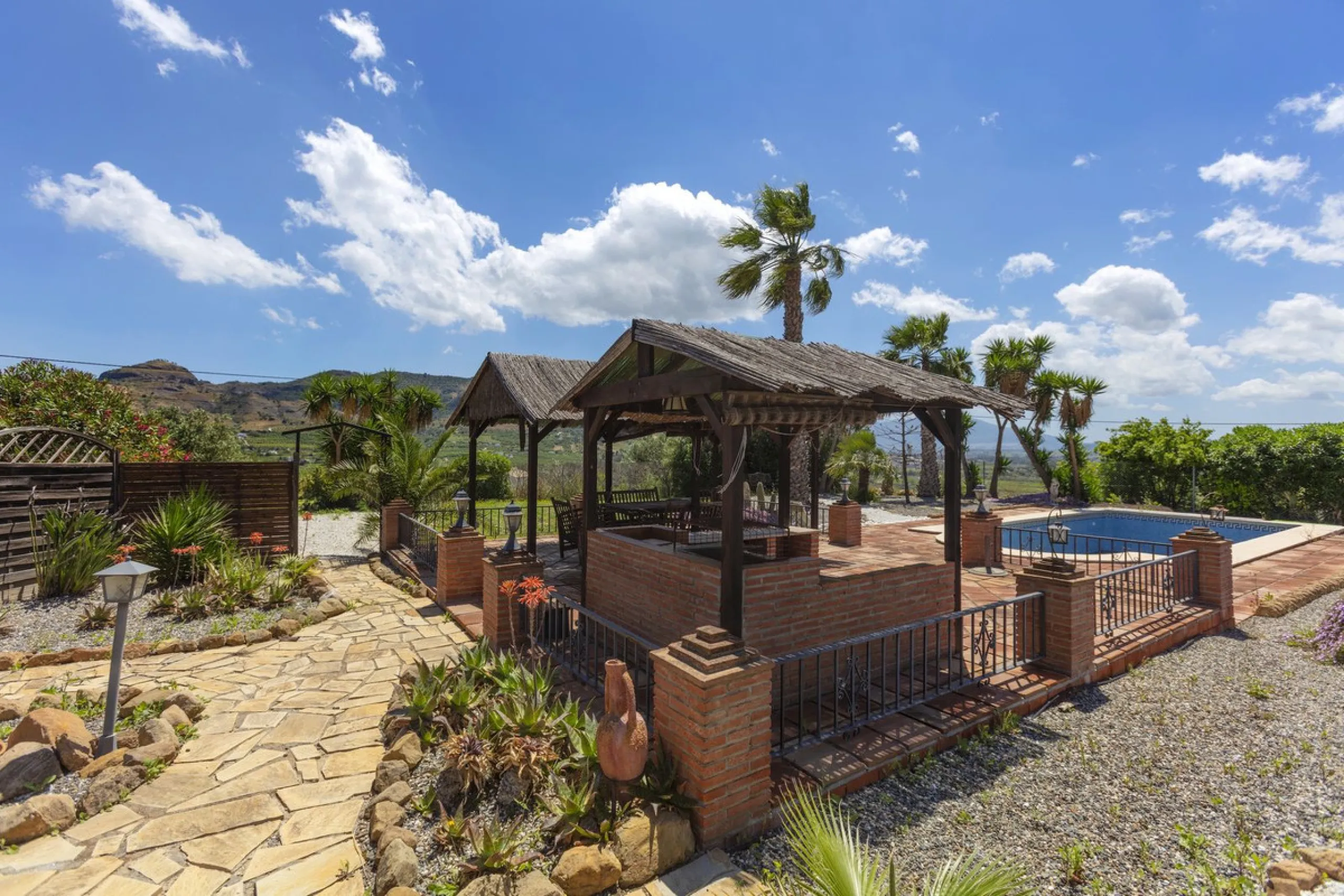 This finca set in an elevated position has impressive mountain views all around it.  The garden is split into different areas each with its own beautiful vibe. Stylish barbecue area by the pool is great for relaxing and welcoming guests.  Main house has t