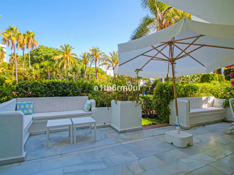 BEACHSIDE • WALKING DISTANCE TO MARBELLA CENTRE & ALL AMENITIES • Cheerful corner ground floor two bedroom apartment just steps from the beach. Located in a very desirable complex with lush mature gardens and swimming pool, right on the promenade, just a 