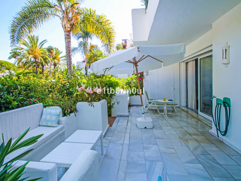 BEACHSIDE • WALKING DISTANCE TO MARBELLA CENTRE & ALL AMENITIES • Cheerful corner ground floor two bedroom apartment just steps from the beach. Located in a very desirable complex with lush mature gardens and swimming pool, right on the promenade, just a 