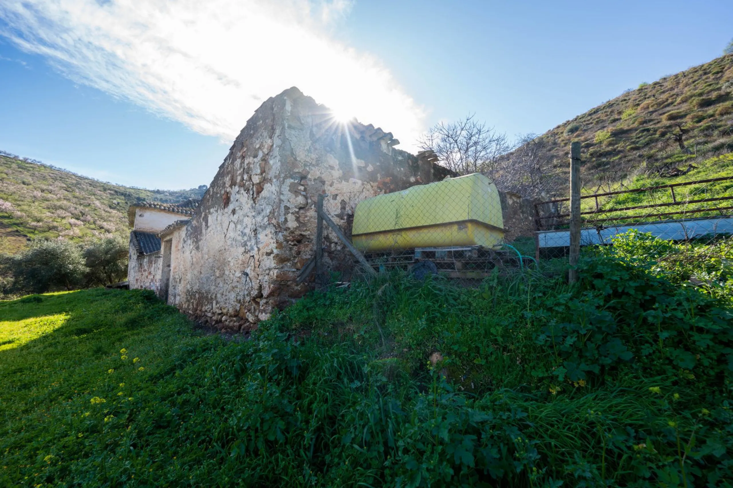 Imagine a place where time seems to stand still—a vast, quiet estate that breathes history in every corner. Two old houses in ruins rise gently from the land, their weathered walls worn by the years yet still standing strong, as if waiting for someone to 