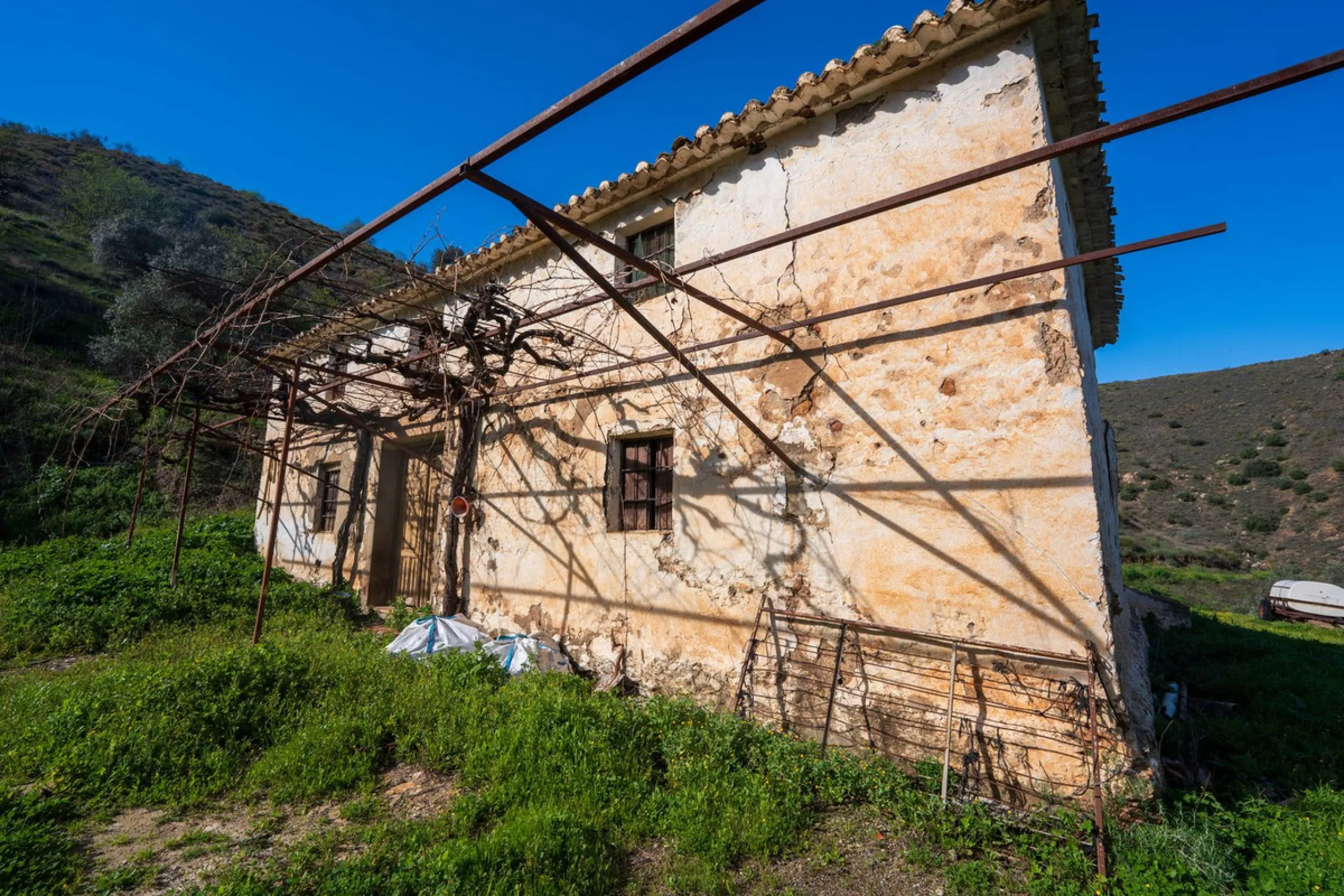 Imagine a place where time seems to stand still—a vast, quiet estate that breathes history in every corner. Two old houses in ruins rise gently from the land, their weathered walls worn by the years yet still standing strong, as if waiting for someone to 