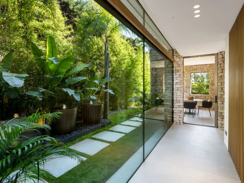 Nestled gracefully upon the verdant slopes of Nueva Andalucía, this villa is a triumph of modern elegance and luxurious design, an embodiment of serene sophistication. As you approach the property, you are greeted by a grand entrance framed by sleek lines