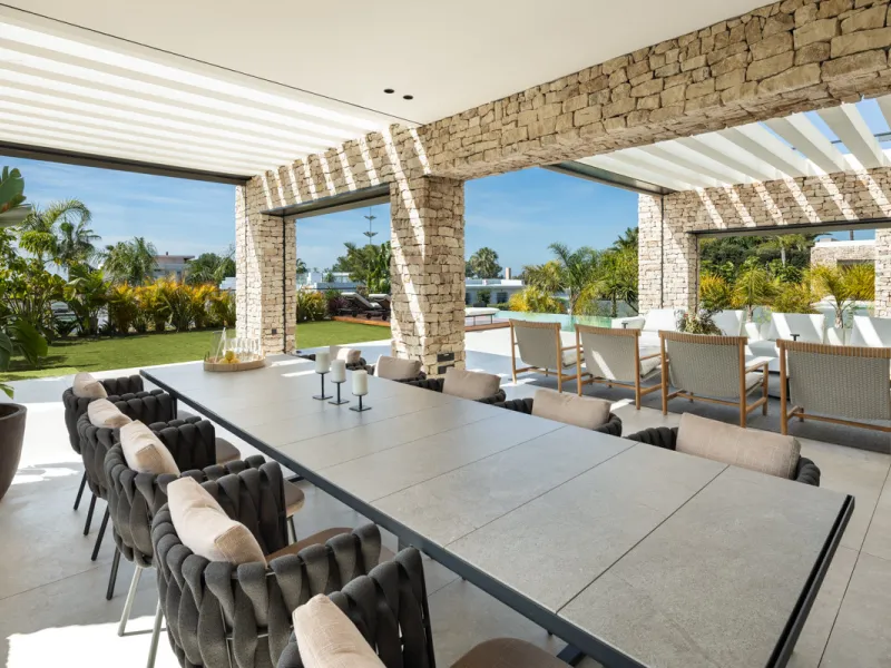 Nestled gracefully upon the verdant slopes of Nueva Andalucía, this villa is a triumph of modern elegance and luxurious design, an embodiment of serene sophistication. As you approach the property, you are greeted by a grand entrance framed by sleek lines