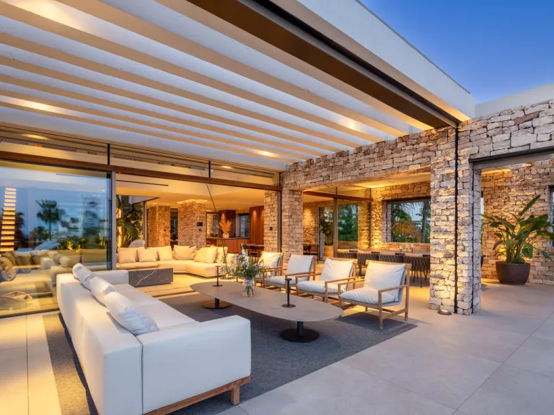 Nestled gracefully upon the verdant slopes of Nueva Andalucía, this villa is a triumph of modern elegance and luxurious design, an embodiment of serene sophistication. As you approach the property, you are greeted by a grand entrance framed by sleek lines
