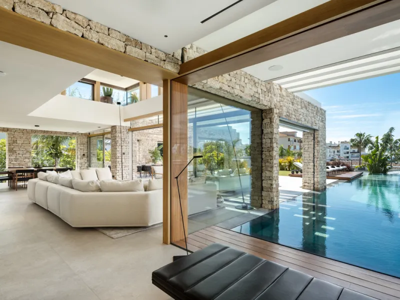 Nestled gracefully upon the verdant slopes of Nueva Andalucía, this villa is a triumph of modern elegance and luxurious design, an embodiment of serene sophistication. As you approach the property, you are greeted by a grand entrance framed by sleek lines