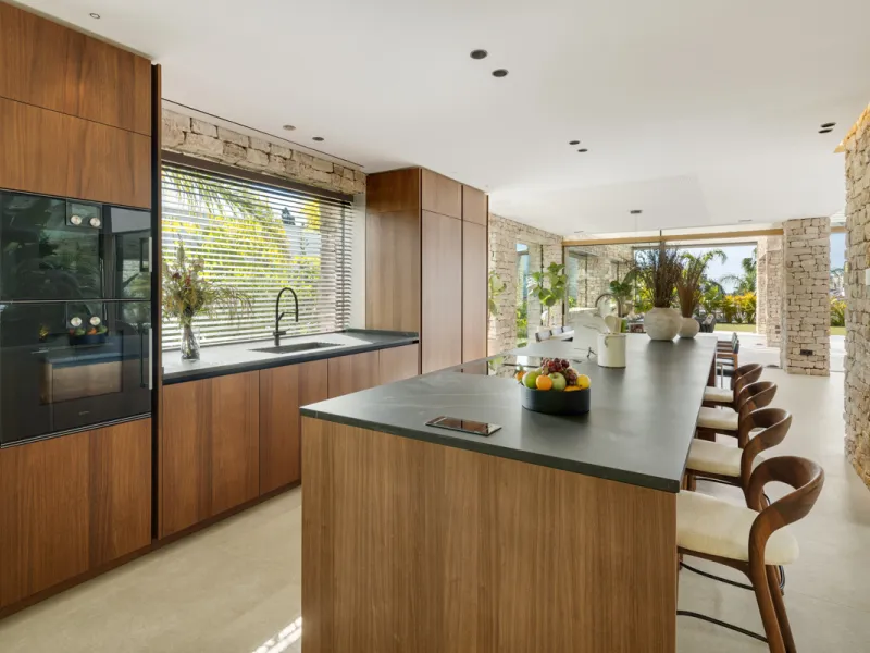 Nestled gracefully upon the verdant slopes of Nueva Andalucía, this villa is a triumph of modern elegance and luxurious design, an embodiment of serene sophistication. As you approach the property, you are greeted by a grand entrance framed by sleek lines