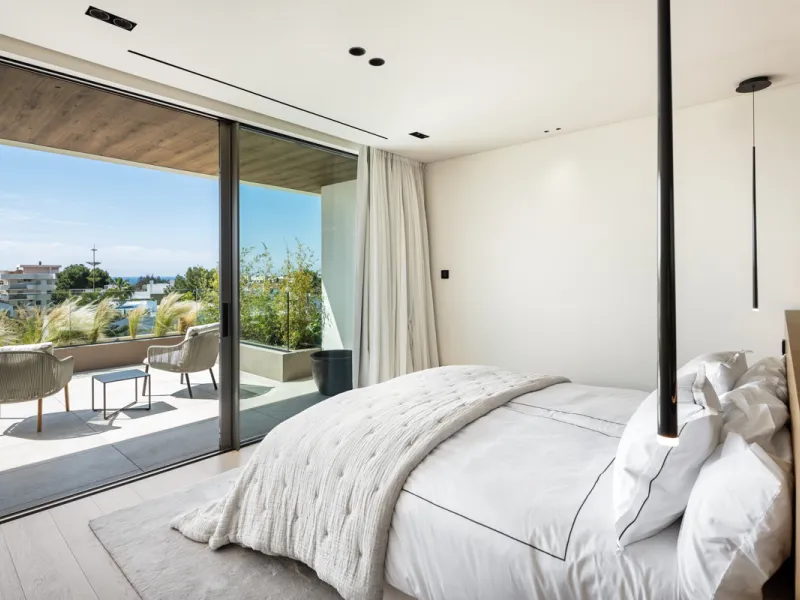 Nestled gracefully upon the verdant slopes of Nueva Andalucía, this villa is a triumph of modern elegance and luxurious design, an embodiment of serene sophistication. As you approach the property, you are greeted by a grand entrance framed by sleek lines