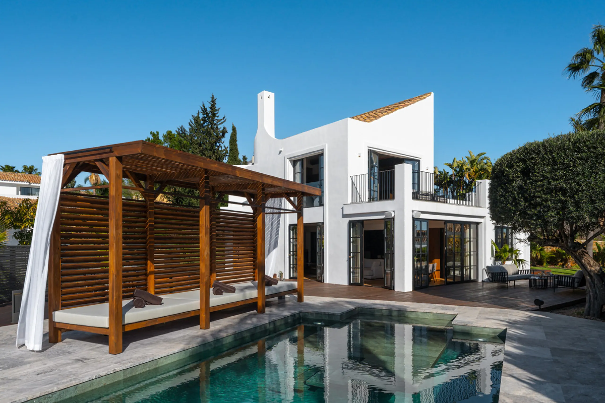 A four-bedroom villa in Nueva Andalucía with open golf and sea views, arranged over multiple levels with a garden-level pool, integrated outdoor kitchen, generous terraces and a private garage.