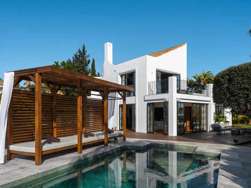 A four-bedroom villa in Nueva Andalucía with open golf and sea views, arranged over multiple levels with a garden-level pool, integrated outdoor kitchen, generous terraces and a private garage.
