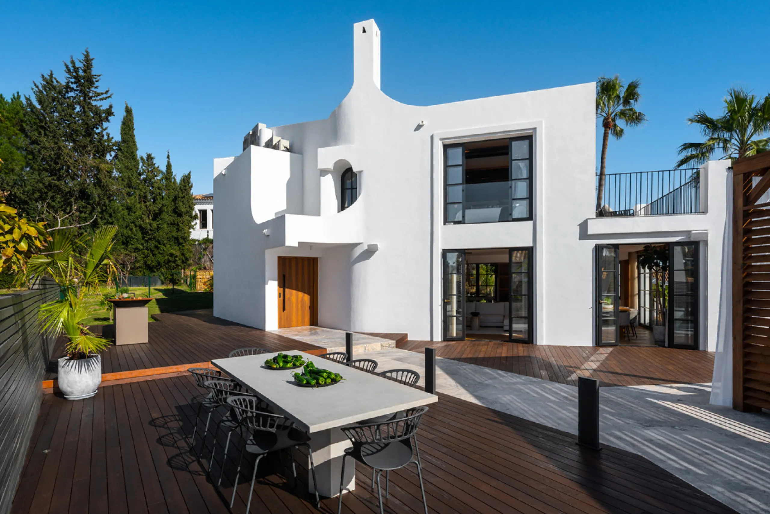 A four-bedroom villa in Nueva Andalucía with open golf and sea views, arranged over multiple levels with a garden-level pool, integrated outdoor kitchen, generous terraces and a private garage.